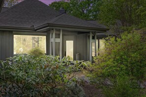 Ein Haus mit überdachter Veranda, großen Fenstern und einem Steinweg, der zum Eingang führt.