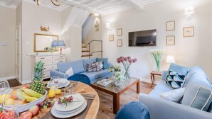 A modern living room with a dining area, featuring a sofa, coffee table, and a dining table set for a meal. - Casa Chiostro in Lucca (Lucca)