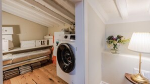 A laundry area with a washing machine, stacked linens, and a wooden floor. - Casa Chiostro in Lucca (Lucca)