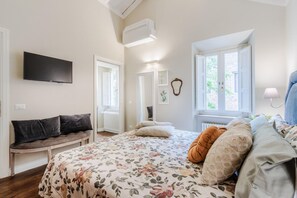 Une chambre à coucher comprenant un lit, un banc, un téléviseur à écran plat, une fenêtre et un radiateur.
