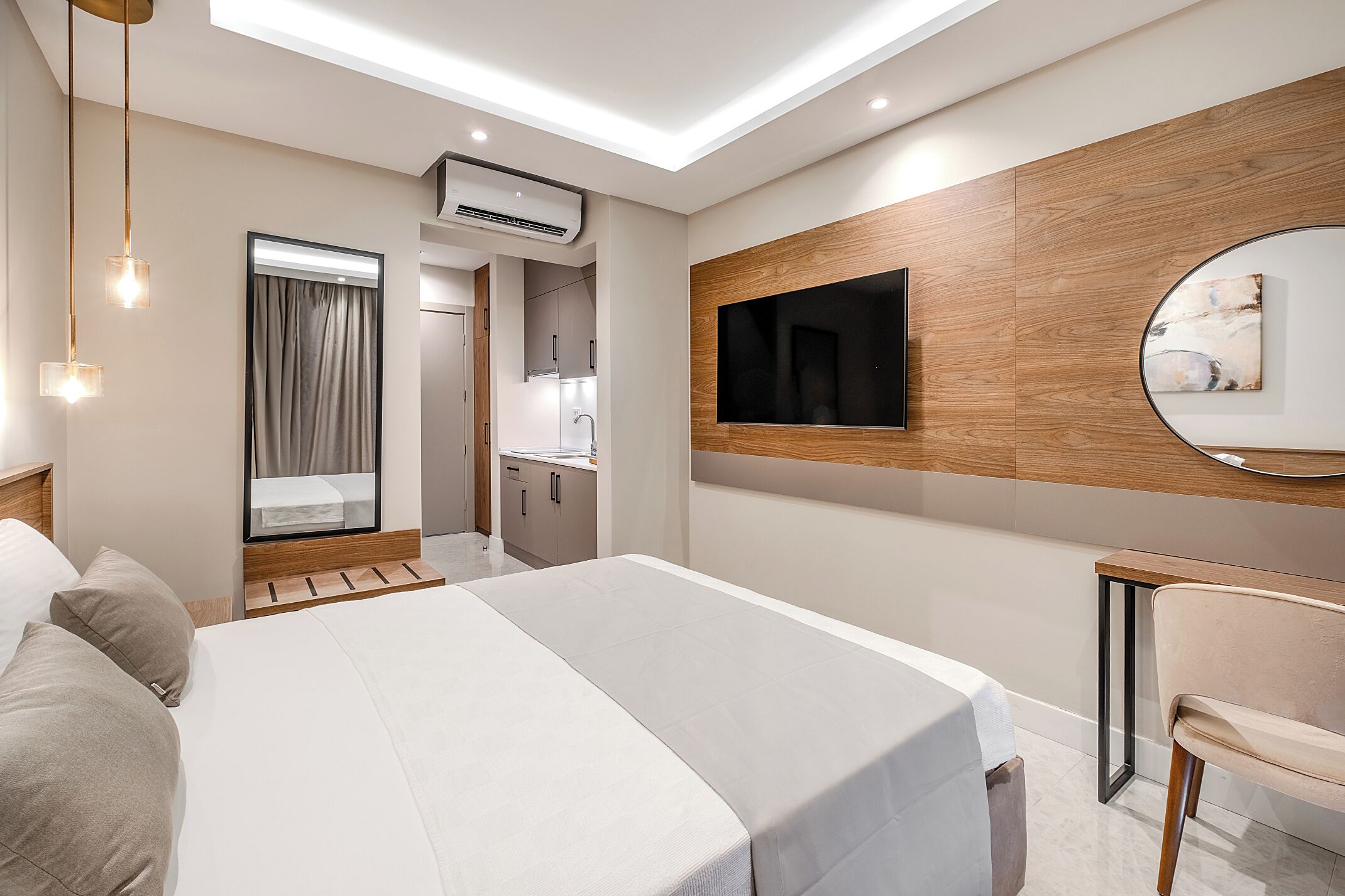 Una habitación de hotel moderna con una cama grande, un escritorio, una silla, un televisor y un espejo.