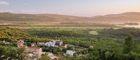 Une ville dont les bâtiments sont entourés d’une végétation luxuriante, avec des collines en arrière-plan.