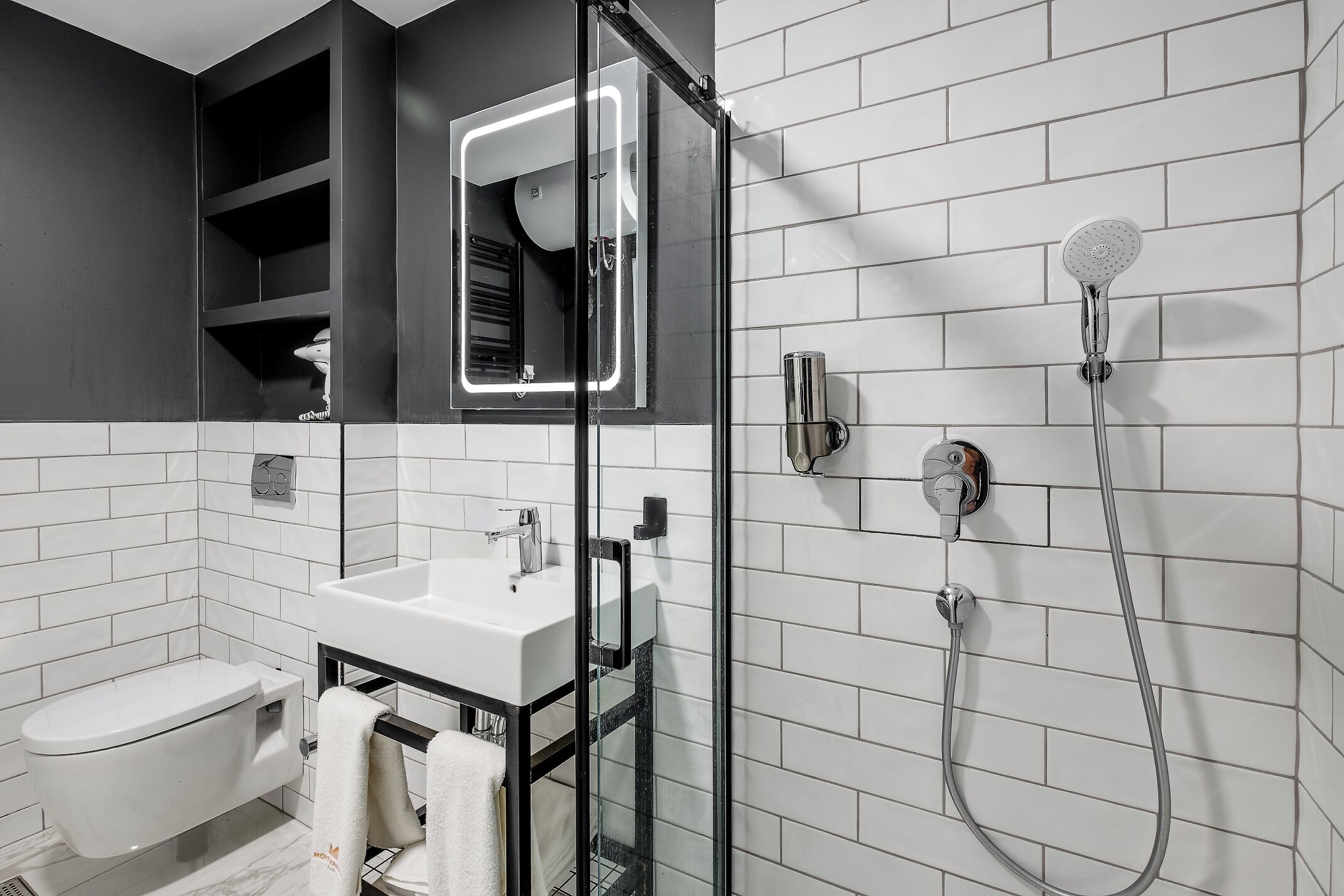 A modern bathroom with a glass-enclosed shower, a white sink, and a toilet.