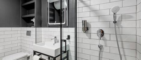 Une salle de bain moderne avec une douche à parois de verre, un lavabo blanc et des toilettes.