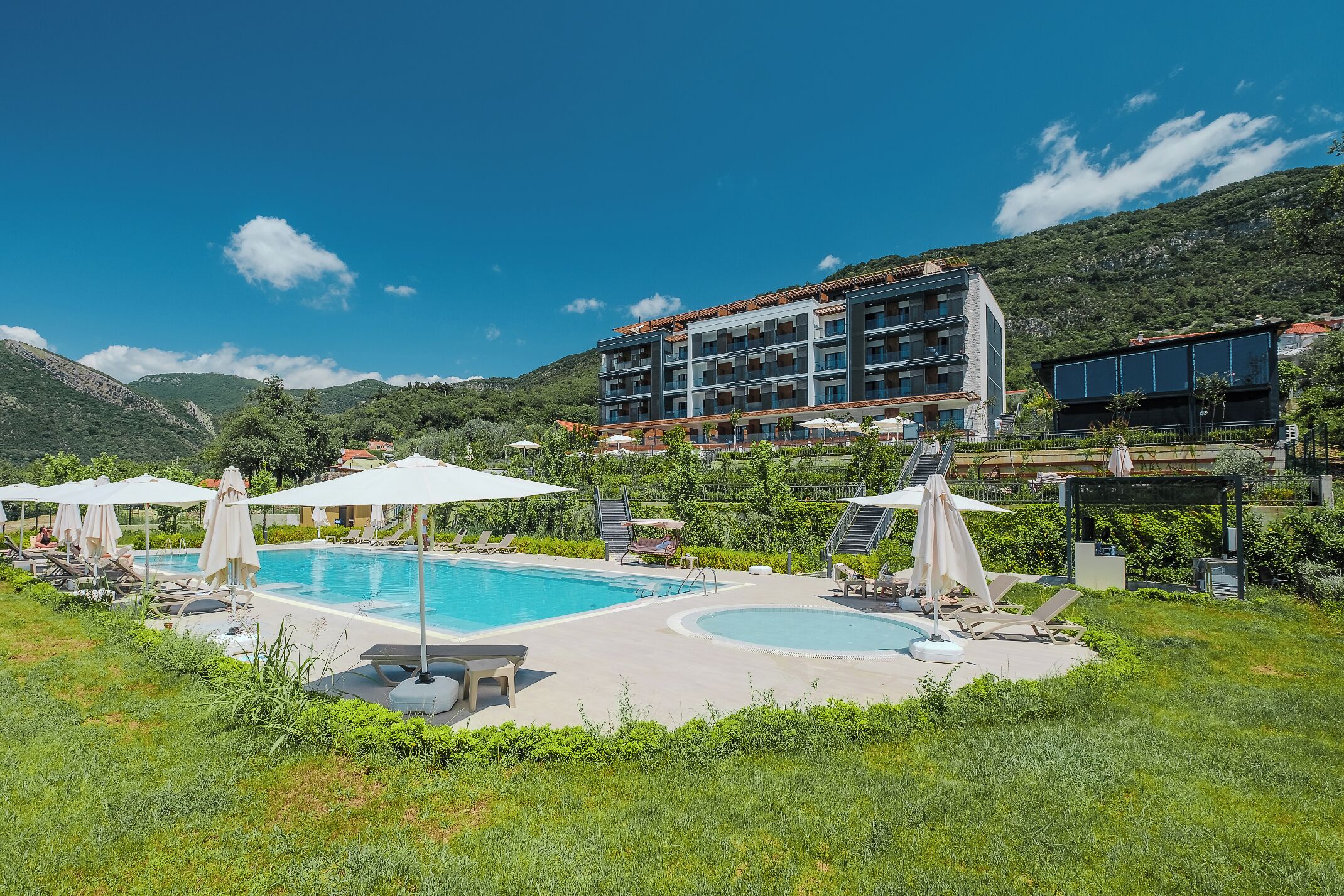 A hotel with a swimming pool, sun loungers, and umbrellas.