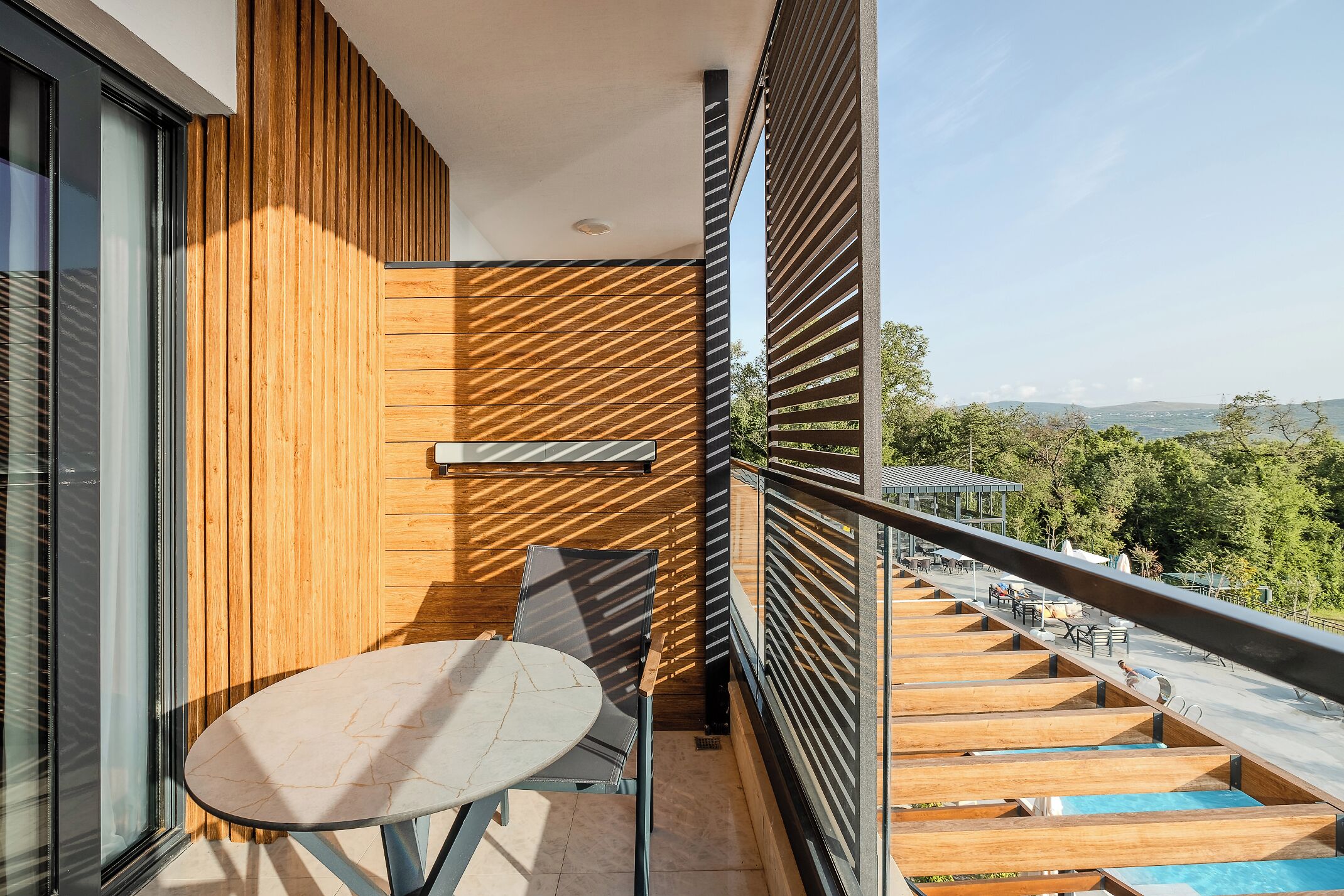 Un balcón con pared de madera, una mesa y sillas.