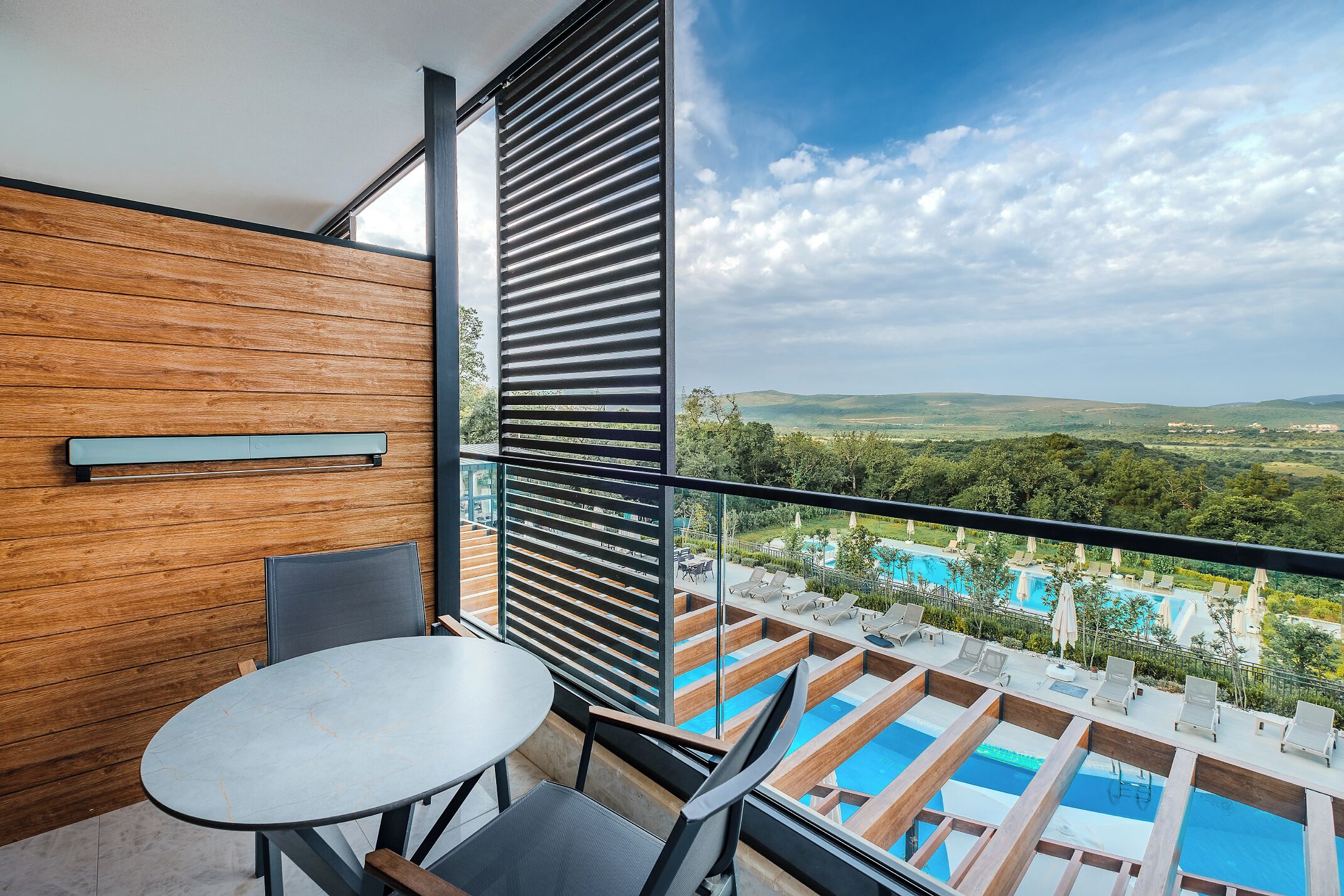 Uma varanda com vista para uma piscina e um muro de madeira.