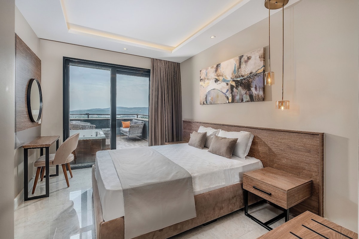A modern hotel room with a large bed, a desk, and a view of the city.