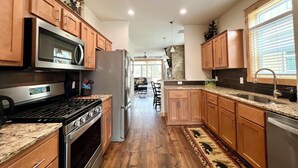 A modern kitchen with wooden cabinets, stainless steel appliances, and a granite countertop. - 2 Kg Beds+ Walk to Ponds, Pool, Hot tub&River. Short Drive to RMNP & Winter Park (Granby)