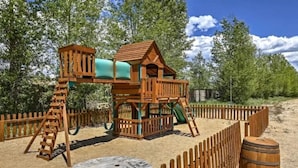 A wooden play structure with a slide and climbing area, surrounded by a wooden fence and a sandpit. - 2 Kg Beds+ Walk to Ponds, Pool, Hot tub&River. Short Drive to RMNP & Winter Park (Granby)
