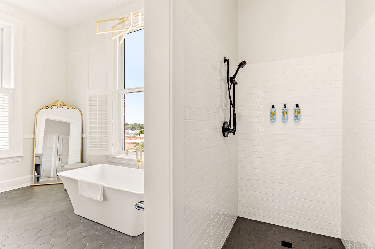 Un bagno con una vasca da bagno bianca, uno specchio grande e una doccia con dettagli neri.