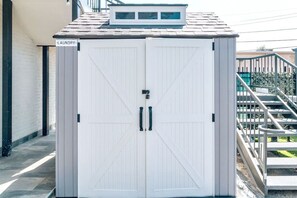 Un lavadero blanco con dos puertas y un pequeño ventanal sobre la puerta.