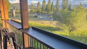 A wooden deck with a view of a river and trees. - Cozy Cabin: Summer paradise on the river (Granby)