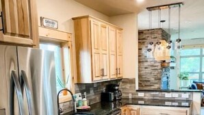 A modern kitchen with wooden cabinets, stainless steel appliances, and a stone backsplash. - Cozy Cabin: Summer paradise on the river (Granby)