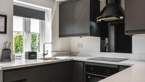 A modern kitchen with a built-in oven, a sink, and a window with a view of greenery.