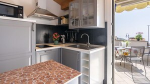 A compact kitchen with a stone countertop, a built-in microwave, and a sink. - Apartment Fico by Interhome (Terzorio)