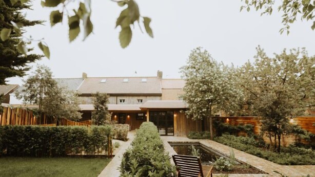 A modern house with a garden, a wooden bench, and a pathway leading to the entrance. - Huyze Ter Bercken with swimming pond by Interhome (De Haan)