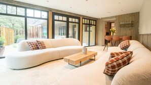 A modern living room with a large sectional sofa, a wooden coffee table, and a dining area with a bar. - Huyze Ter Bercken with swimming pond by Interhome (De Haan)