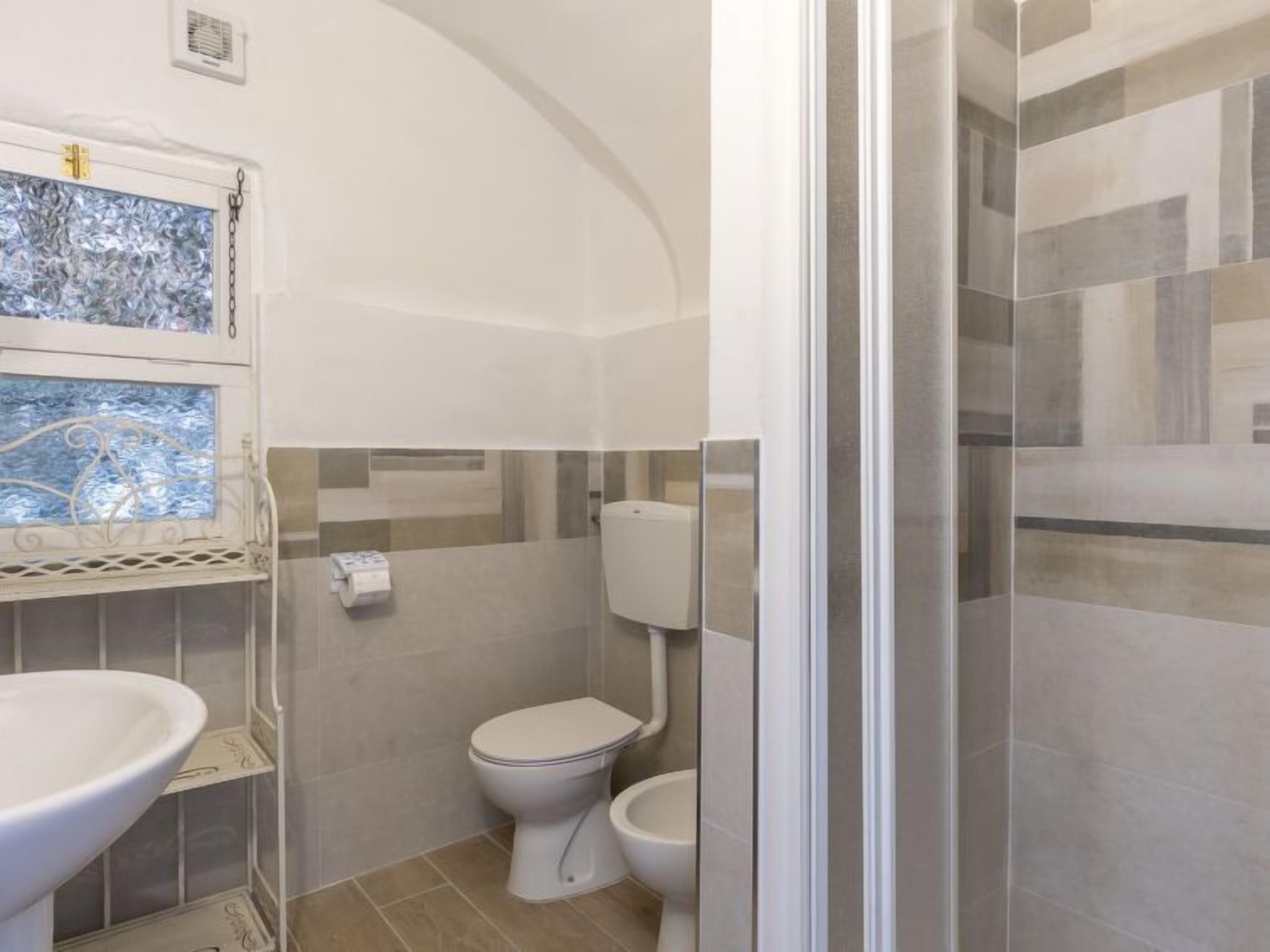 A bathroom with a toilet, a sink, and a shower area.
