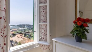 Une pièce avec une fenêtre donnant sur un paysage, une commode blanche et un miroir doté d’un cadre décoratif.
