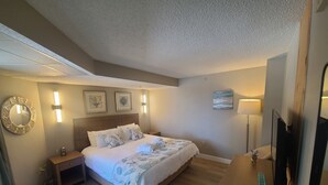 A hotel room with a large bed, bedside tables, a flat-screen TV, a desk with a lamp, and artwork on the walls. - Ocean View King Suit Heated Pools Myrtle Beach  (Myrtle Beach)