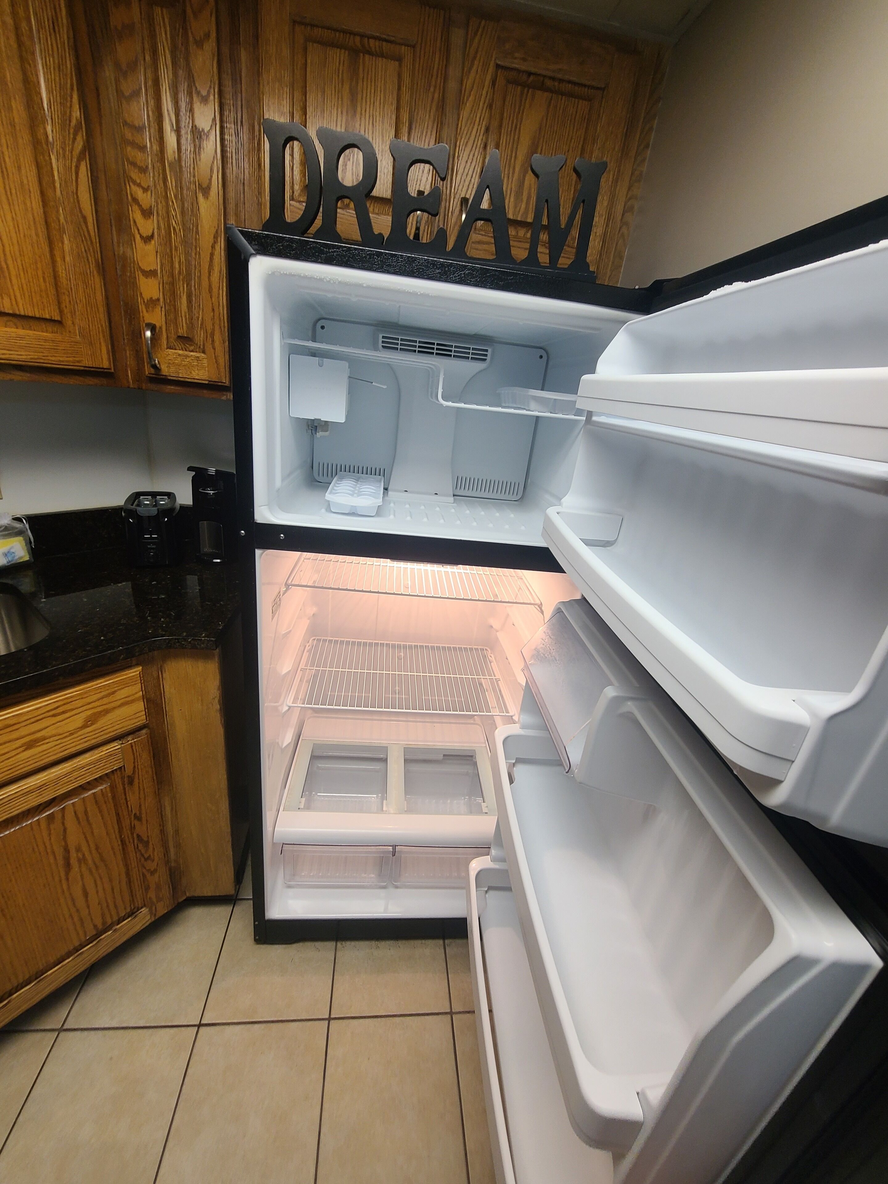 A kitchen with wooden cabinets, a black countertop, and a white refrigerator with the word "DREAM" on it.