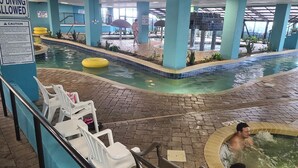 An indoor swimming pool area with a diving board, lounge chairs, and a hot tub. - Ocean View King Suit Heated Pools Myrtle Beach  (Myrtle Beach)