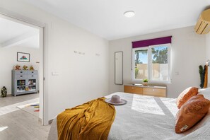 A bedroom with a bed, a window with a view, a wardrobe, and a bedside table.