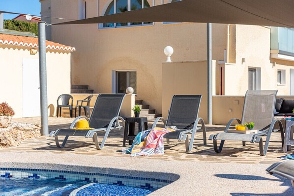 A poolside area with lounge chairs, a small table, and a potted plant.