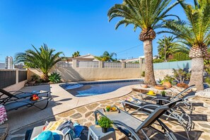 A swimming pool area with lounge chairs and a palm tree.