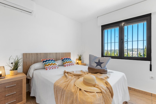 A bedroom with a bed, two nightstands, a window with a view, and a decorative hat on the bed.