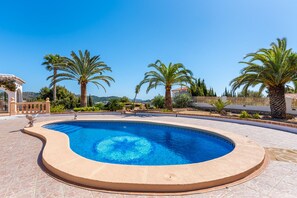 A swimming pool with a circular design, surrounded by palm trees and a clear blue sky.