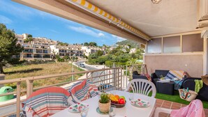 A balcony with a table set for dining, outdoor seating, and a view of a residential area. - Apartamento Zeus 6 - PlusHolidays (Calpe)