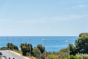 A coastal road with street lamps, a speed limit sign, and a clear view of the sea. - Apartamento Zeus 6 - PlusHolidays (Calpe)