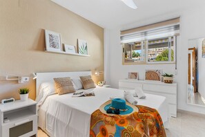 Ein modernes Hotelzimmer mit einem großen Bett, Nachttischen, einem Schreibtisch und einem Fenster mit Blick auf Gebäude.
