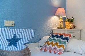 A bedroom with a bed, pillows, a nightstand, a lamp, and a wall socket. - Apartamento Zeus 6 - PlusHolidays (Calpe)