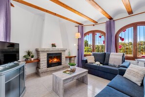 Una sala de estar con chimenea, un sofá, una mesa de centro y una televisión.
