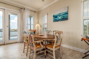 A dining area with a round table, chairs, and a view of the outdoors.