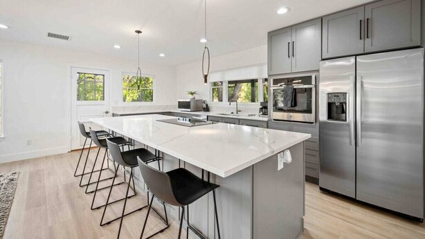 A modern kitchen with a large island, stainless steel appliances, and bar stools.