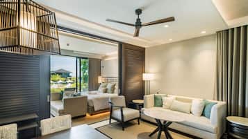 A modern hotel room with a balcony, a ceiling fan, a sofa, a dining table, and a view of the outdoors.