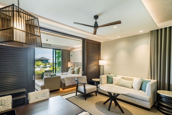 A modern hotel room with a balcony, a ceiling fan, a sofa, a dining table, and a view of the outdoors. - Discovery Samal (Samal)
