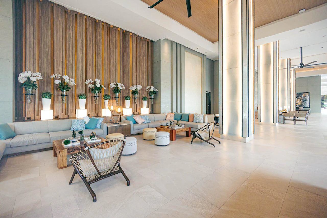 Un amplio salón con un sofá grande, una mesa de centro y plantas decorativas.