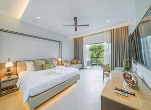 A modern hotel room with a large bed, a desk with a remote control, and a view of greenery outside. - Discovery Samal (Samal)