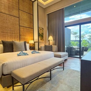 Habitación de hotel moderna con una cama grande, una banca, un escritorio y vistas al exterior.