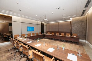 Ein Konferenzraum mit langem Tisch, Stühlen, einem Fernsehbildschirm und modernem Deckenstil.