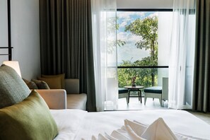 A hotel room with a large bed, a sofa, and a balcony with a table and chairs. - Discovery Samal (Samal)