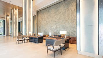 A spacious lobby with a reception desk, several chairs, and a large textured wall.