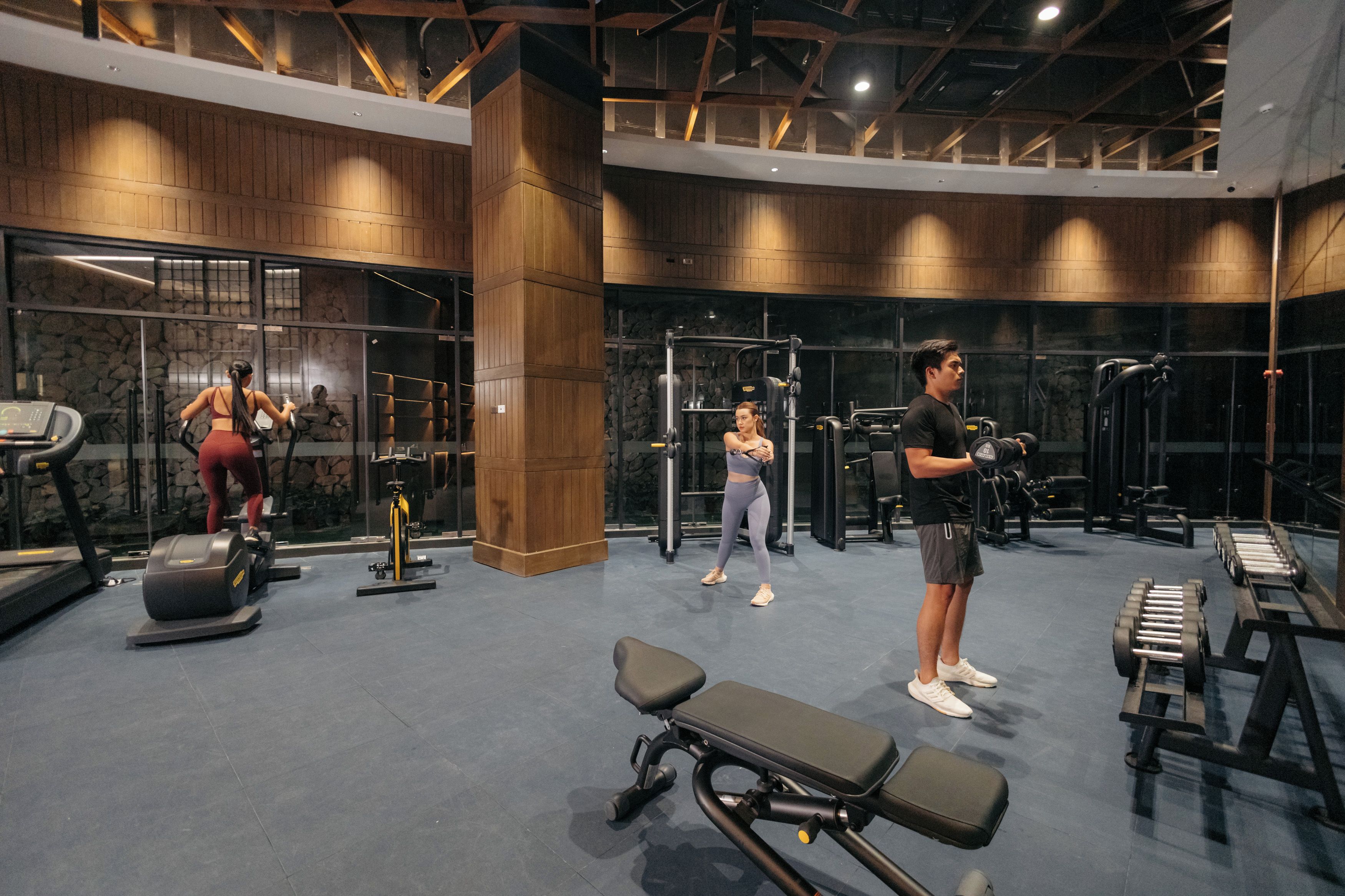 A gym with cardio equipment, weight machines, and a bench.