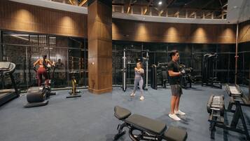 A gym with cardio equipment, weight machines, and a bench.