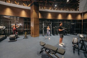 Une salle de sport équipée de machines de cardio, d’appareils de musculation et d’un banc.